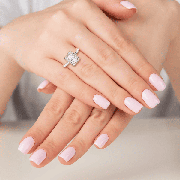 A lady's folded hands with a emerald-cut diamond heirloom ring on her finger.