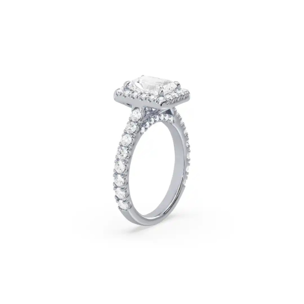 The side view of a white gold emerald cut engagement ring revealing the secret halo of pave set diamonds.