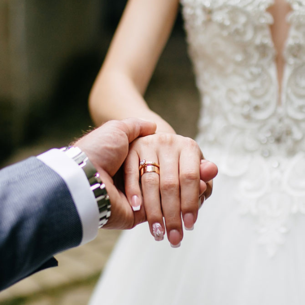 A groom holding his bride's hand at the altar, showcasing unique wedding bands from by Jose Jewellers, Benoni.