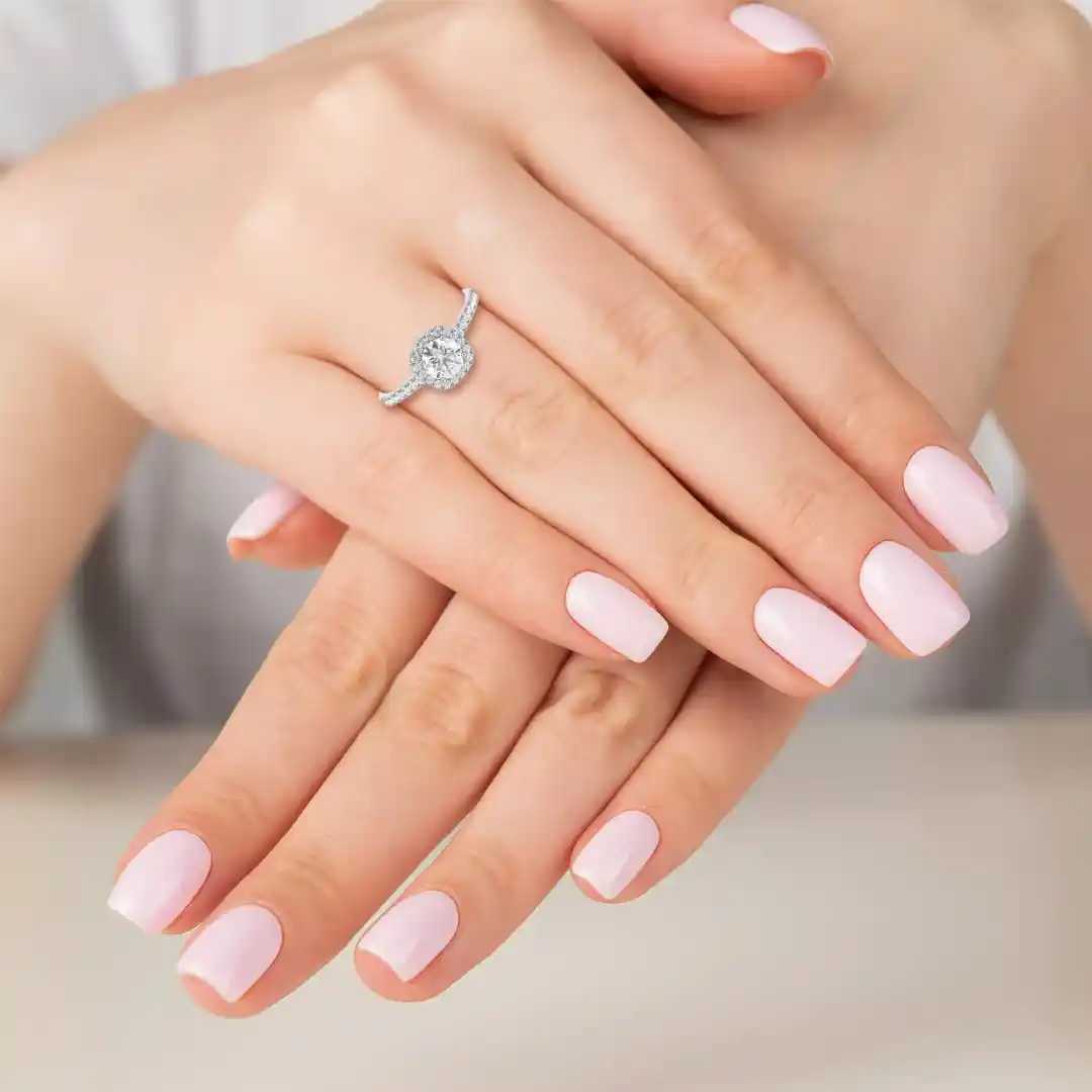 A model wears a halo cushion lab grown diamond engagement piece on her ring finger.